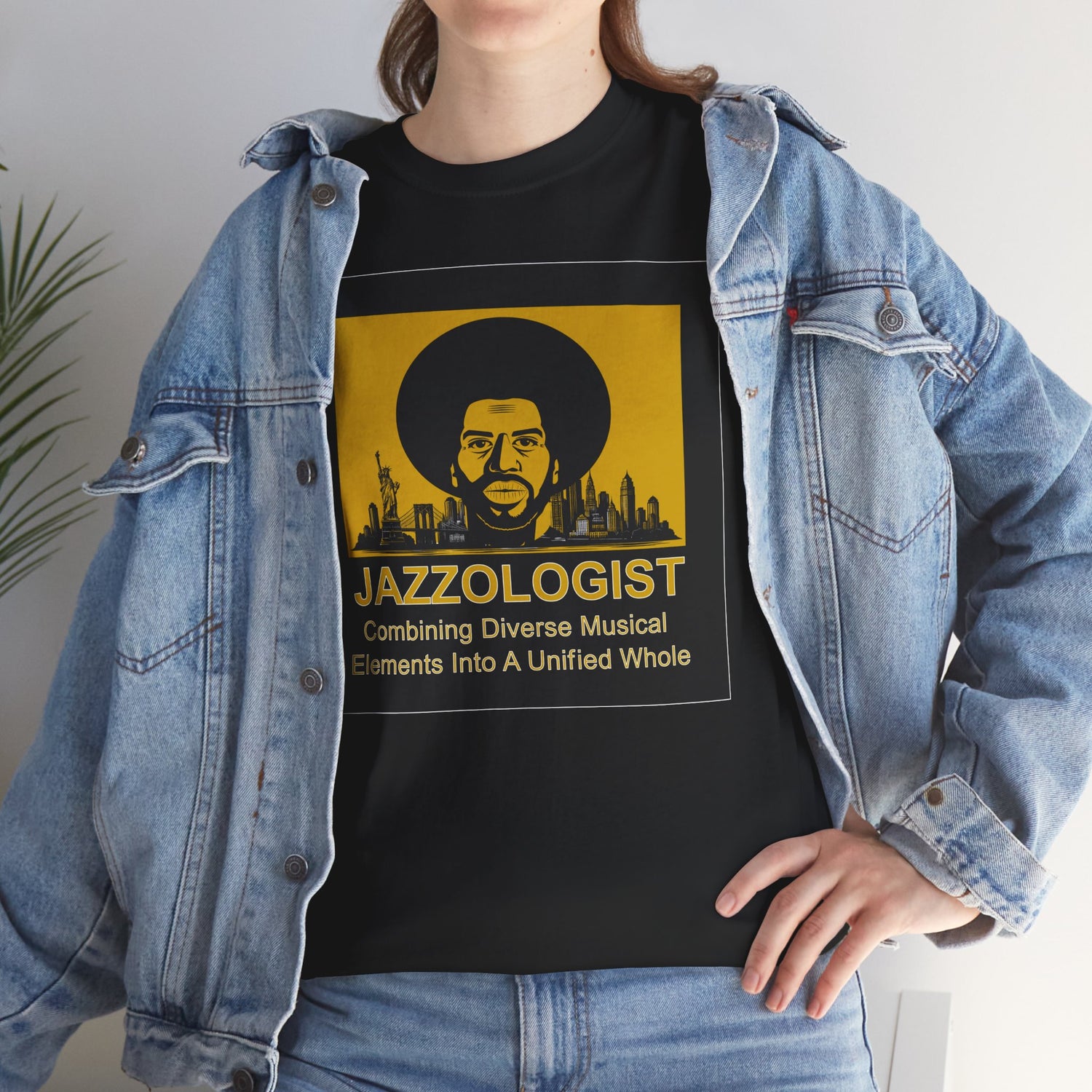 Person wearing a black t-shirt with a yellow graphic and text, paired with a denim jacket.